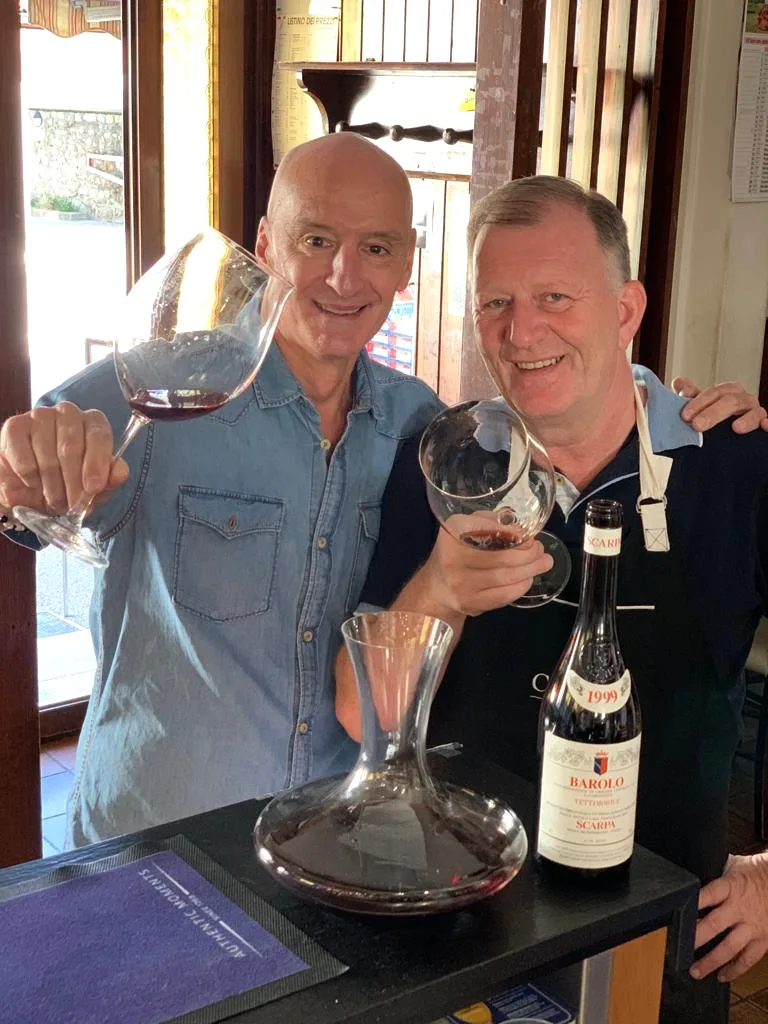 Fabio e un ospite brindano con un Barolo, caraffa e bottiglia sul tavolo
